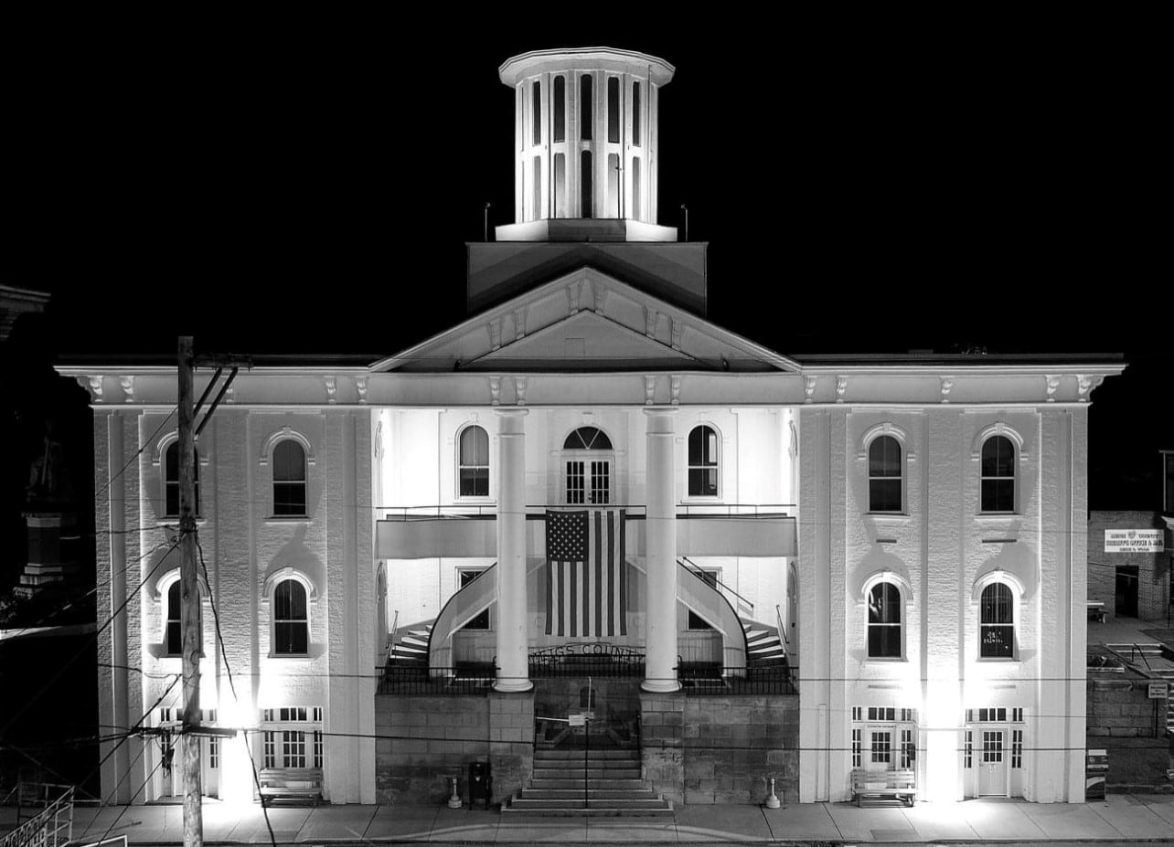The Meigs County Courthouse floodlit at night, its columns, pediment and cupola standing out against a black sky.